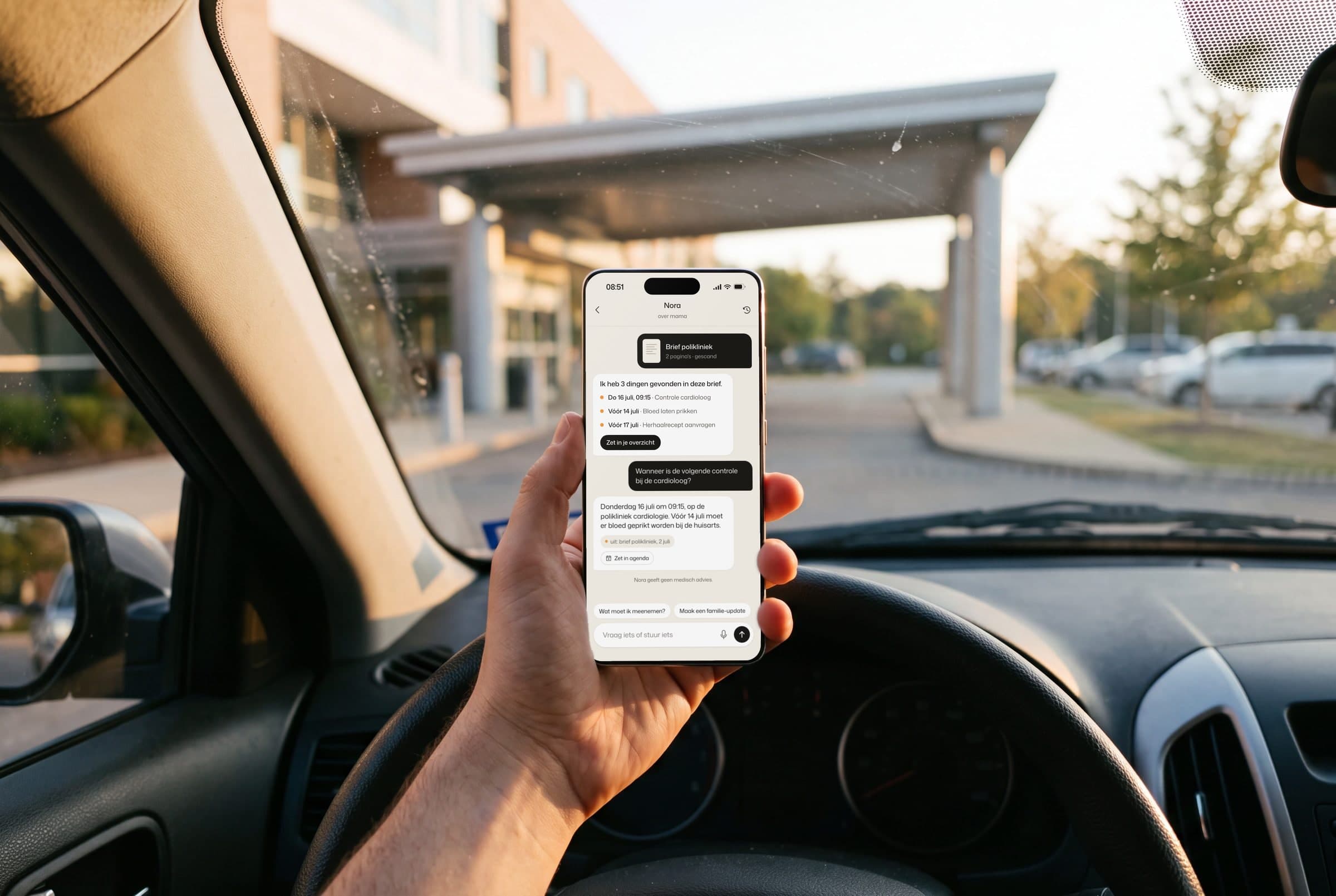 Een hand houdt een telefoon vast in een geparkeerde auto voor een ziekenhuis.