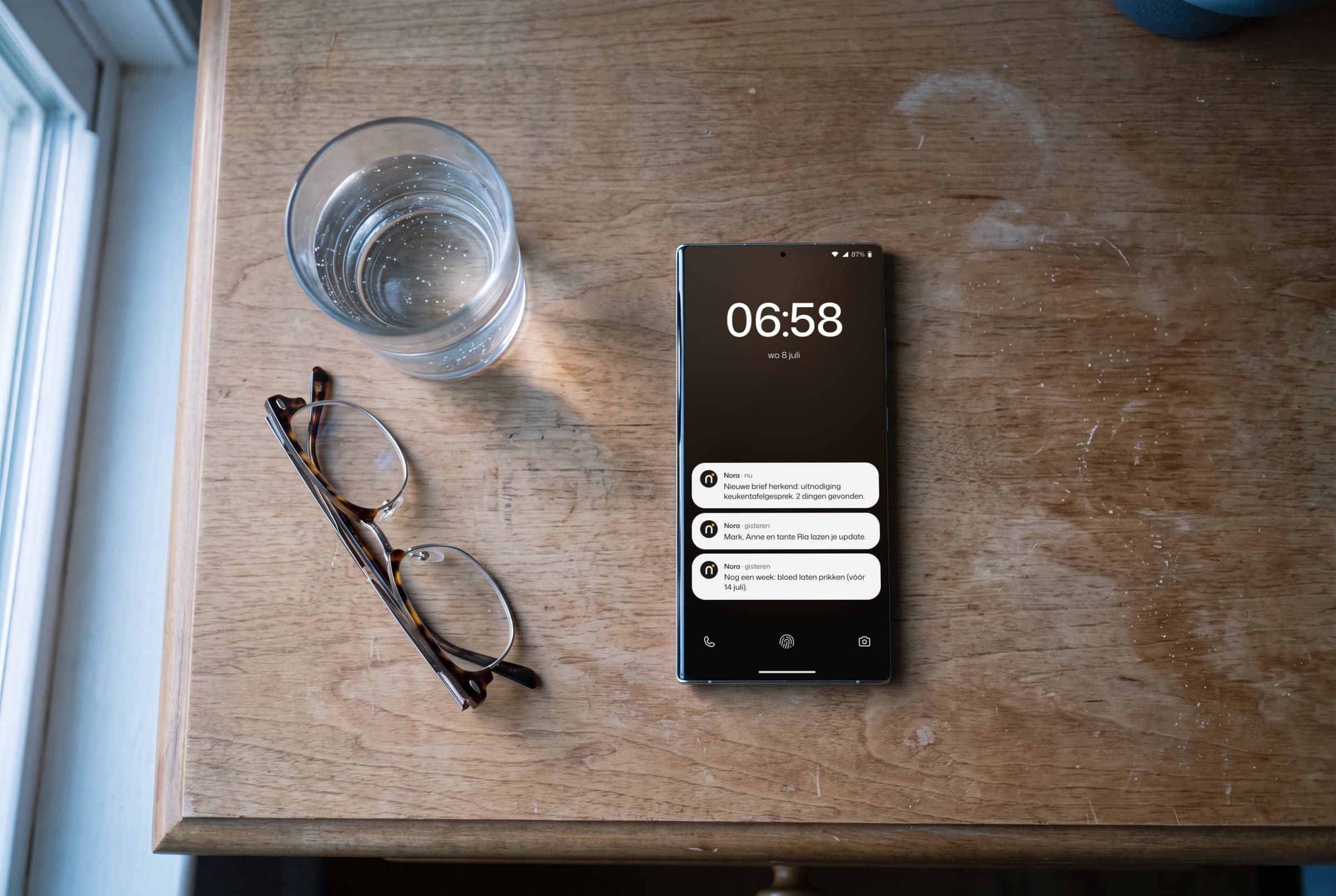 Een telefoon ligt bij zonsopgang op het nachtkastje naast een leesbril.